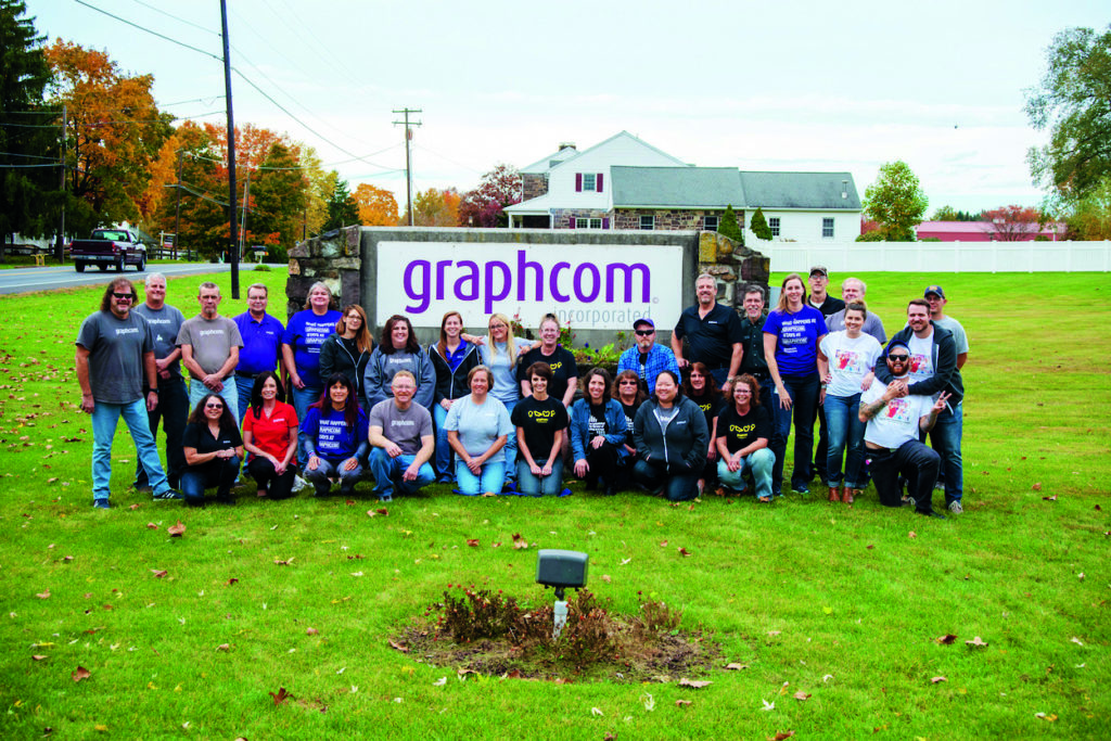 graphcom team photo in front of welcome sign